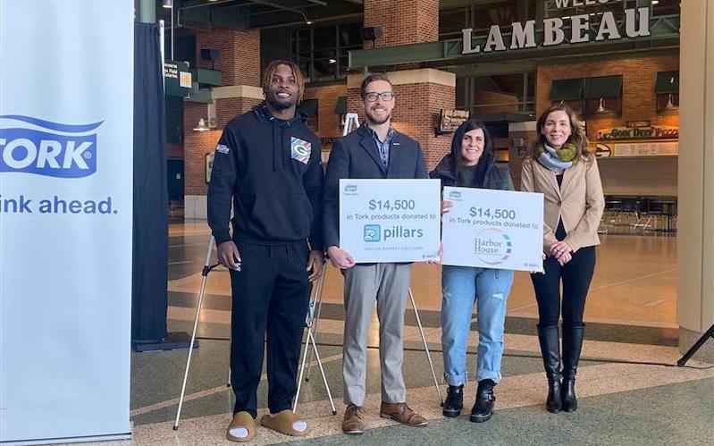 Representatives from The Green Bay Packers and Tork shown holding signs for the $14,500 that was donated.